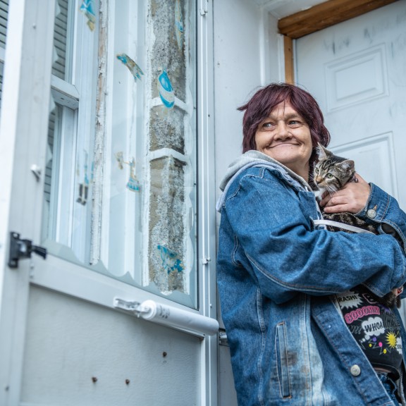 person holding cat in front door of their home