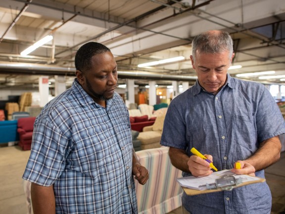 two men look at a clipboard