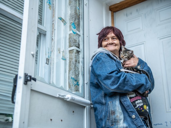 woman standing in her doorway, holding a cat