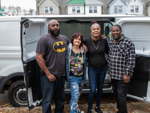four people stand in front of a van