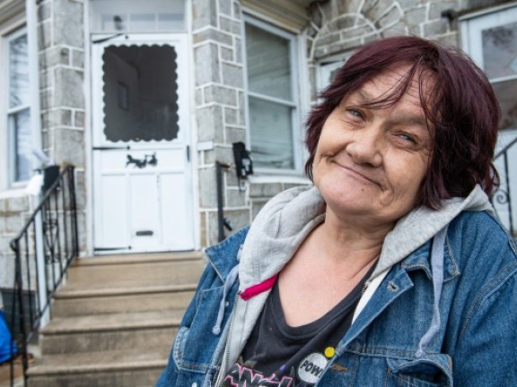 woman smiling in front of her home