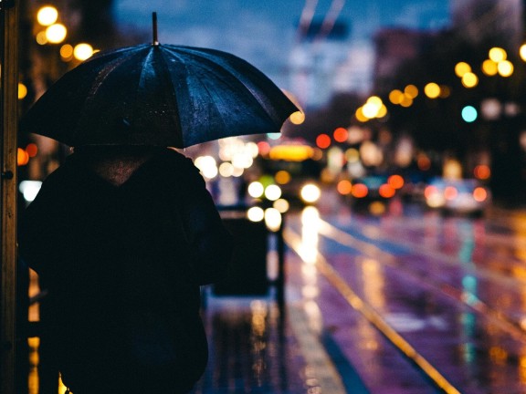 silhouette of person against blurry rainy city