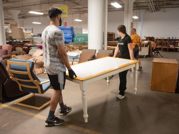 two volunteers carrying table through pfb warehouse