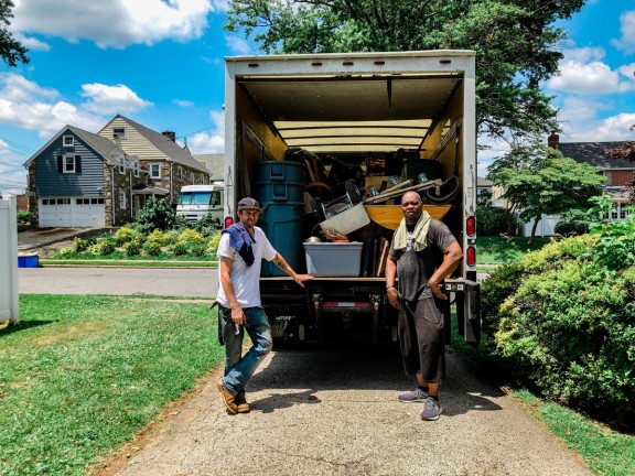 two workers in front of a full truck on a sunny day