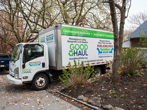 good haul truck backed into a suburban driveway with greenery all around