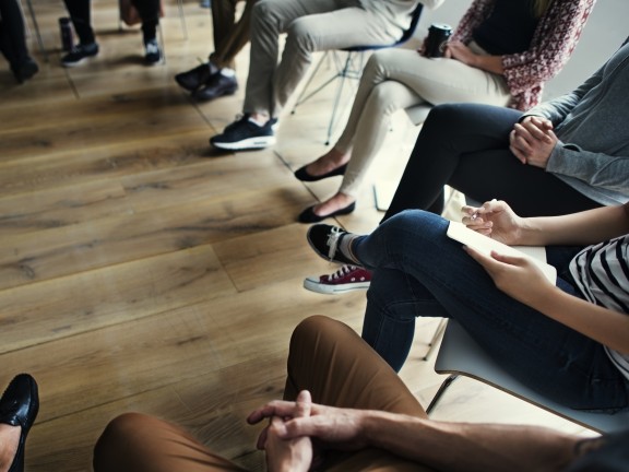 people meeting seated in chairs in a circle wood floor