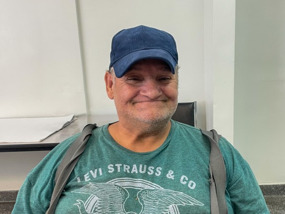 participant smiling with navy hat and green shirt