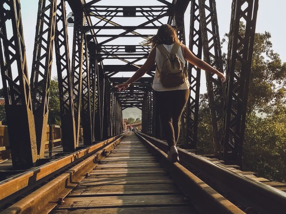 woman balancing on a train track bridge