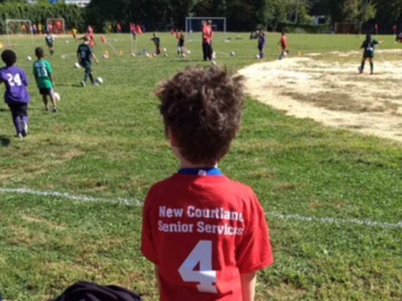 child sitting near soccer field