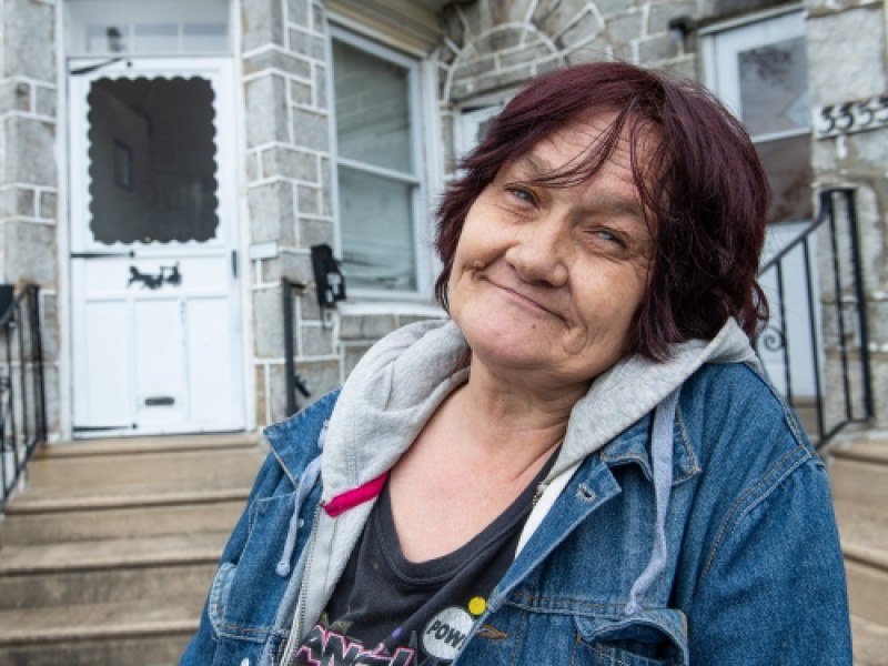 woman smiling in front of her home