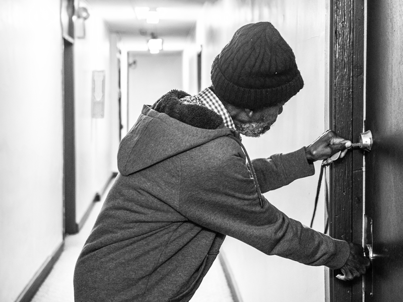 man opening a door in a hallway, black and white image