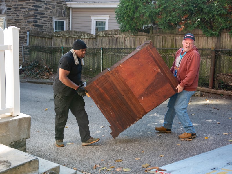 two movers hauling a dresser