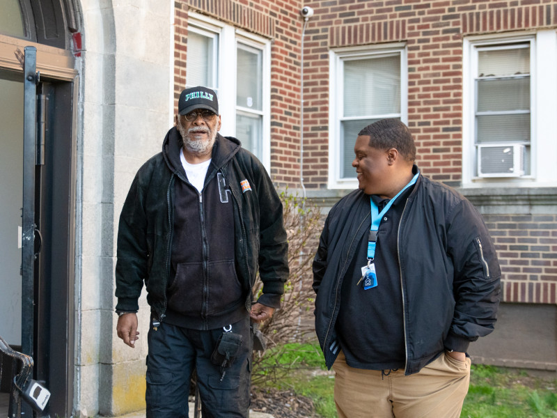 staff and participant standing outside an apartment sharing a laugh