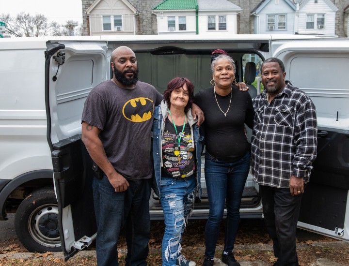 four people stand in front of a van