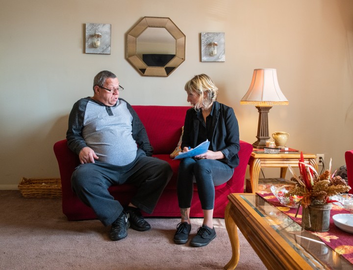 case worker sitting on couch with program participant doing home visit