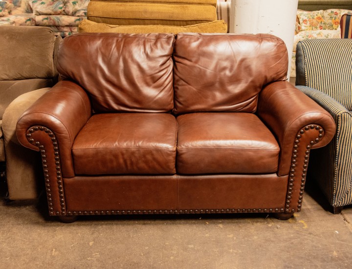 brown leather couch centered in a warehouse