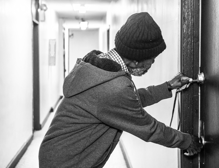 man opening a door in a hallway, black and white image