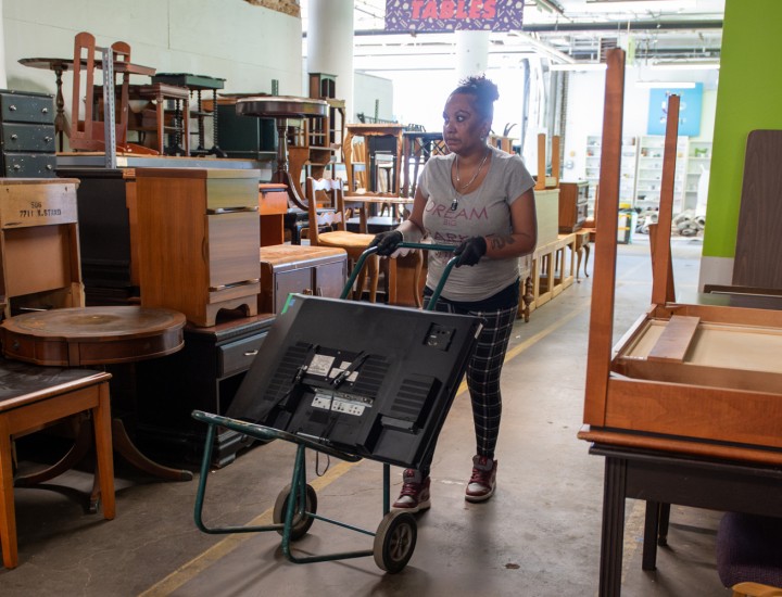 Ednara pushing a tv on a dolly in the Furniture Bank