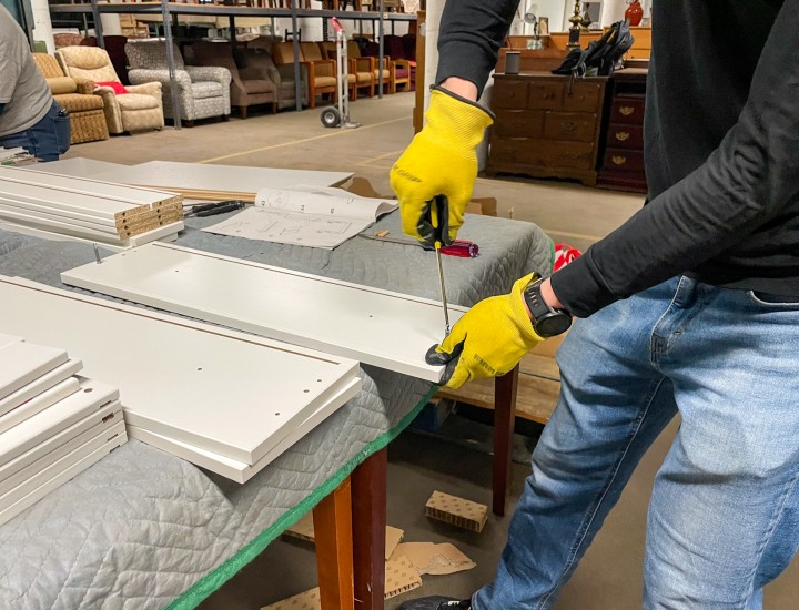 volunteer assembling a piece of furniture with a screwdriver 