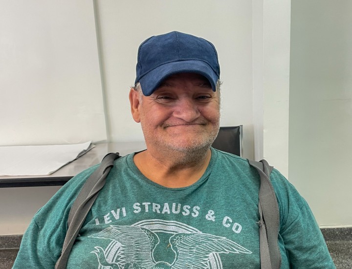 participant smiling with navy hat and green shirt