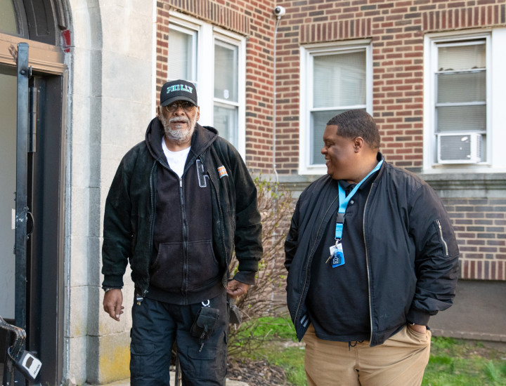 staff and participant standing outside an apartment sharing a laugh