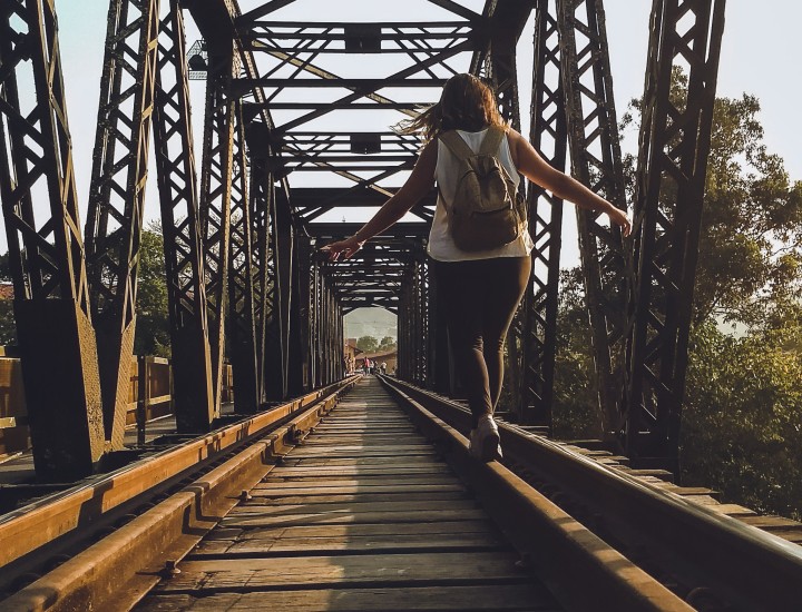 woman balancing on a train track bridge