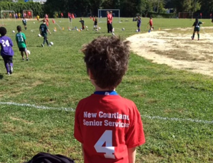 child sitting near soccer field